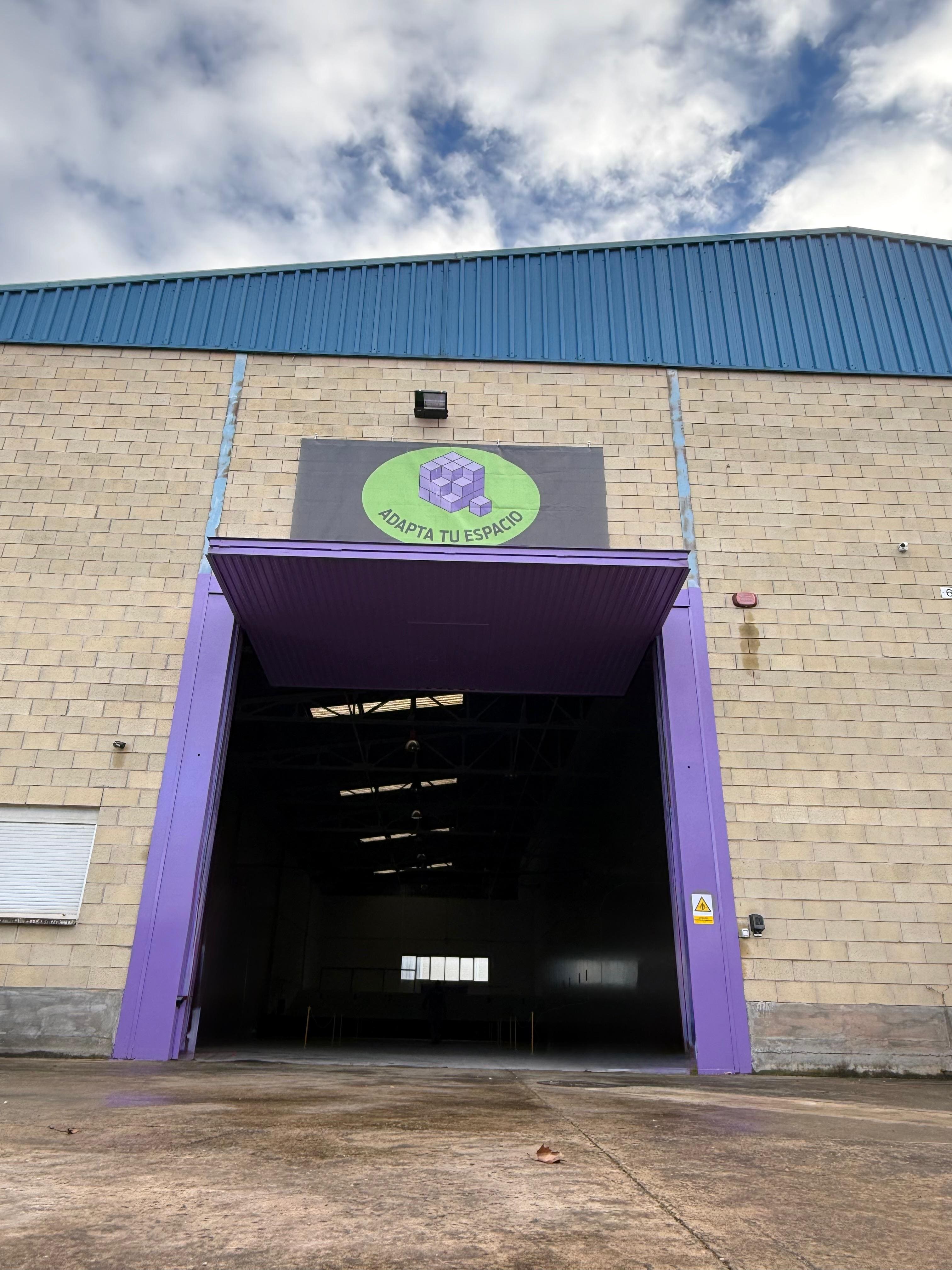 Fachada exterior del pabellón de Adapta Tu Espacio con acceso principal y rótulo identificativo de la marca.